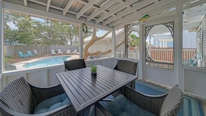 Une terrasse couverte avec une piscine, du mobilier d’extérieur et une vue sur le jardin arrière.