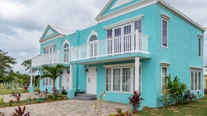A two-story building with a light blue exterior, white trim, and a balcony with white railings. - Summers Dream....  your dreams become a reality. (Negril)
