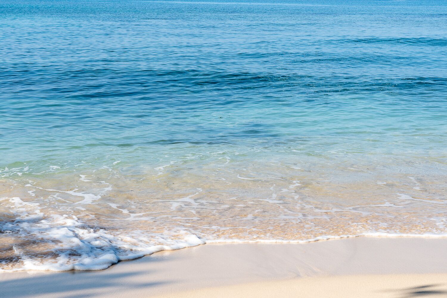 A beach with clear water and a sandy shore.