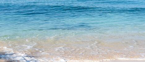 A beach with clear water and a sandy shore.