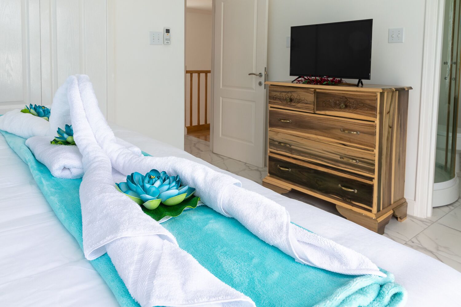 A hotel room with a bed, a wooden dresser, and a television.