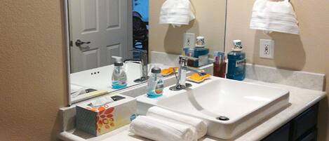 Une salle de bain avec un double lavabo, un miroir et des articles de toilette posés sur le comptoir.