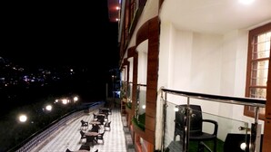 Ein Balkon mit Sitzgelegenheit und Blick auf die beleuchtete Stadt.