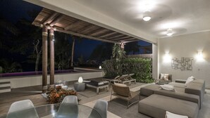 Un espacio exterior moderno con porche cubierto, zona de estar y piscina.