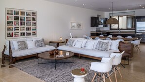 Una sala de estar moderna con un sofá seccional, una mesa de centro y un comedor con sillas blancas.
