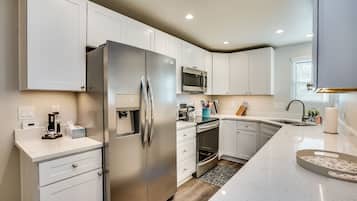 A modern kitchen with white cabinetry, stainless steel appliances, and a large island with a microwave and toaster.