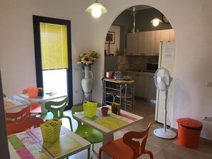 A cozy dining area with a table set for two, a vase with sunflowers, and a kitchen in the background. - B&b Paolo e Daniela (Carbonia)