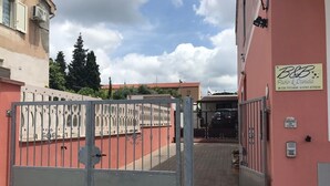 Una entrada cerrada a un edificio con una pared exterior rosa, un letrero que dice 'B&B Paolo & Daniela', y un cielo despejado.