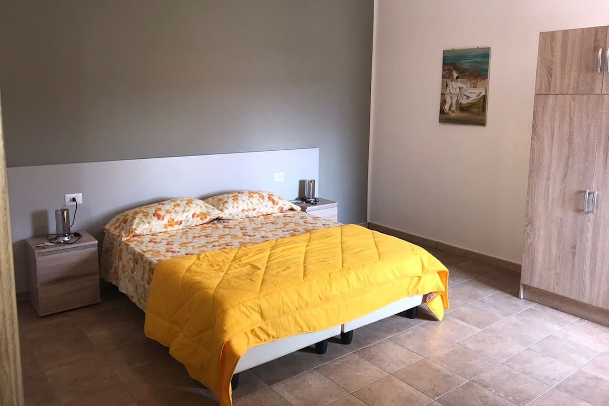 A bedroom with a bed, nightstands, a wardrobe, and a painting on the wall.