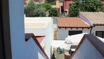 Zona residencial com vista para uma casa de telhado vermelho, parede externa branca e um pequeno espaço de pátio com mesa e cadeiras.