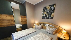 Un dormitorio moderno con una cama doble, mesitas de noche, un espejo y una obra de arte en la pared.