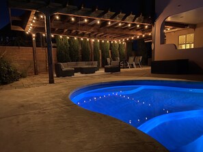A swimming pool with a blue-lit edge, a covered patio with string lights, and outdoor furniture. - Heated Pool•AmazingViews•4 Bed 3 Bath•Great Location•Horseshoe Bend (Page)