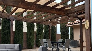 En utomhusplats med en pergola, sittgrupper och ett bord.