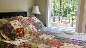 Un dormitorio con una cama grande, una ventana con cortinas y una lámpara.