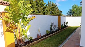 A garden with a white wall, a tiled pathway, and various plants. - Holiday home with fenced private pool (CONIL DE LA FRONTERA)