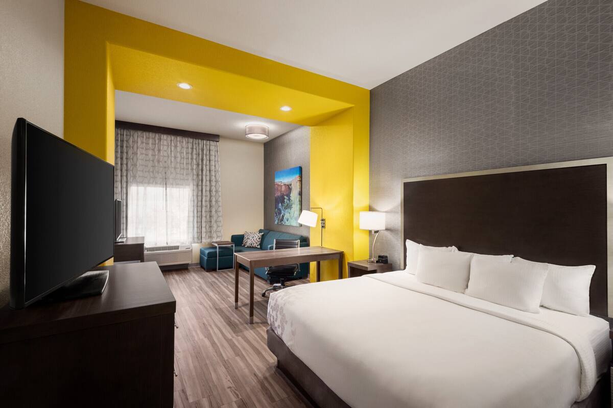 Une chambre d’hôtel avec un lit, un bureau, une télévision et un canapé.