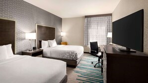 A hotel room with two beds, a TV, a desk, and a chair.