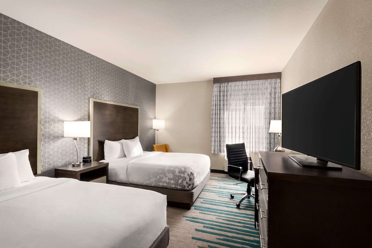 Une chambre d’hôtel avec deux lits, une télévision, un bureau et une chaise.