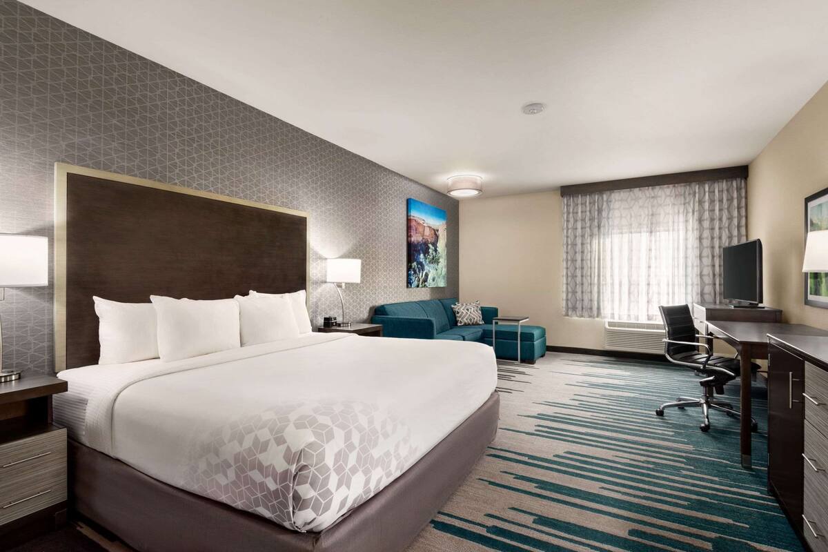 Une chambre d’hôtel avec un grand lit, un bureau, une chaise, un canapé et une télévision.