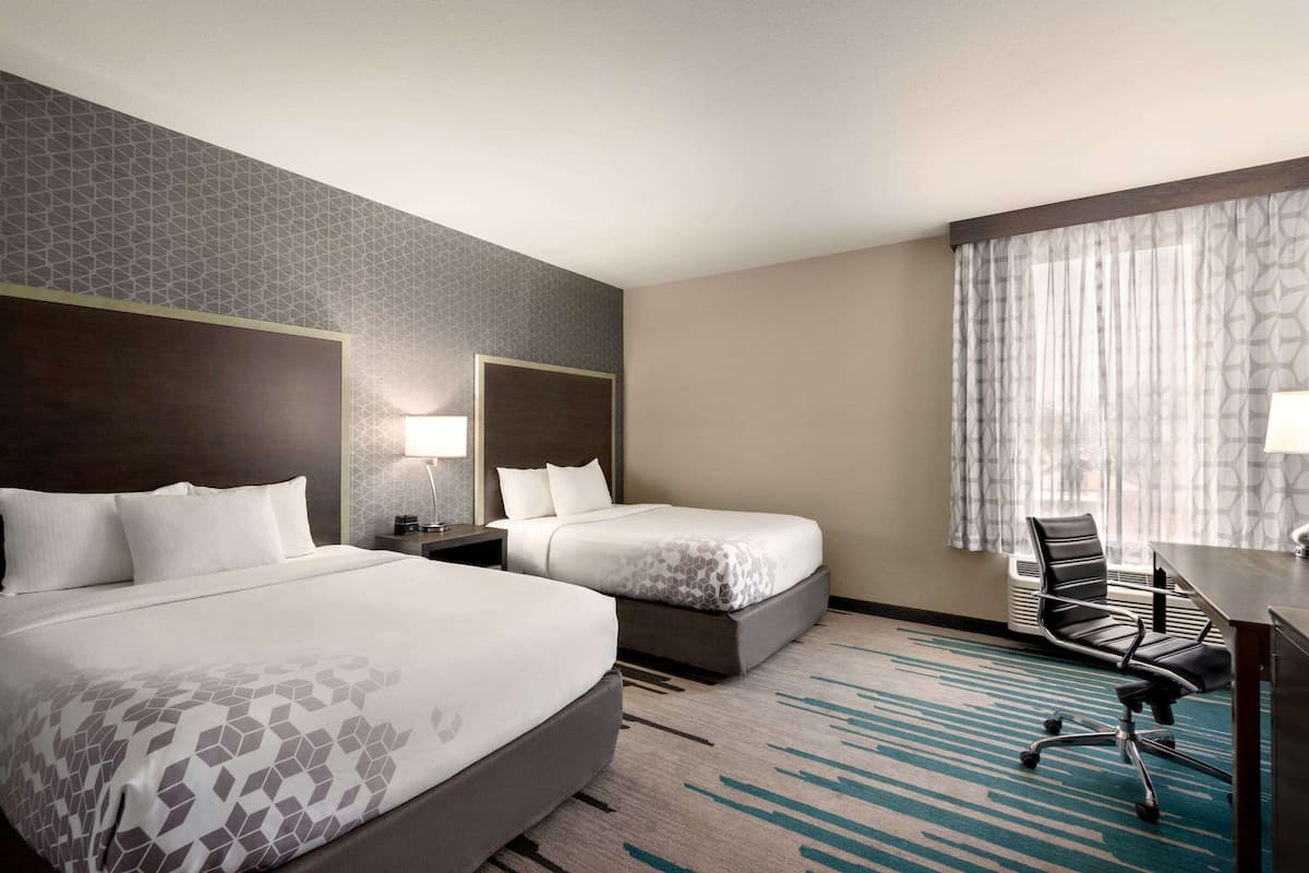 Une chambre d’hôtel avec deux lits, un bureau et une chaise.