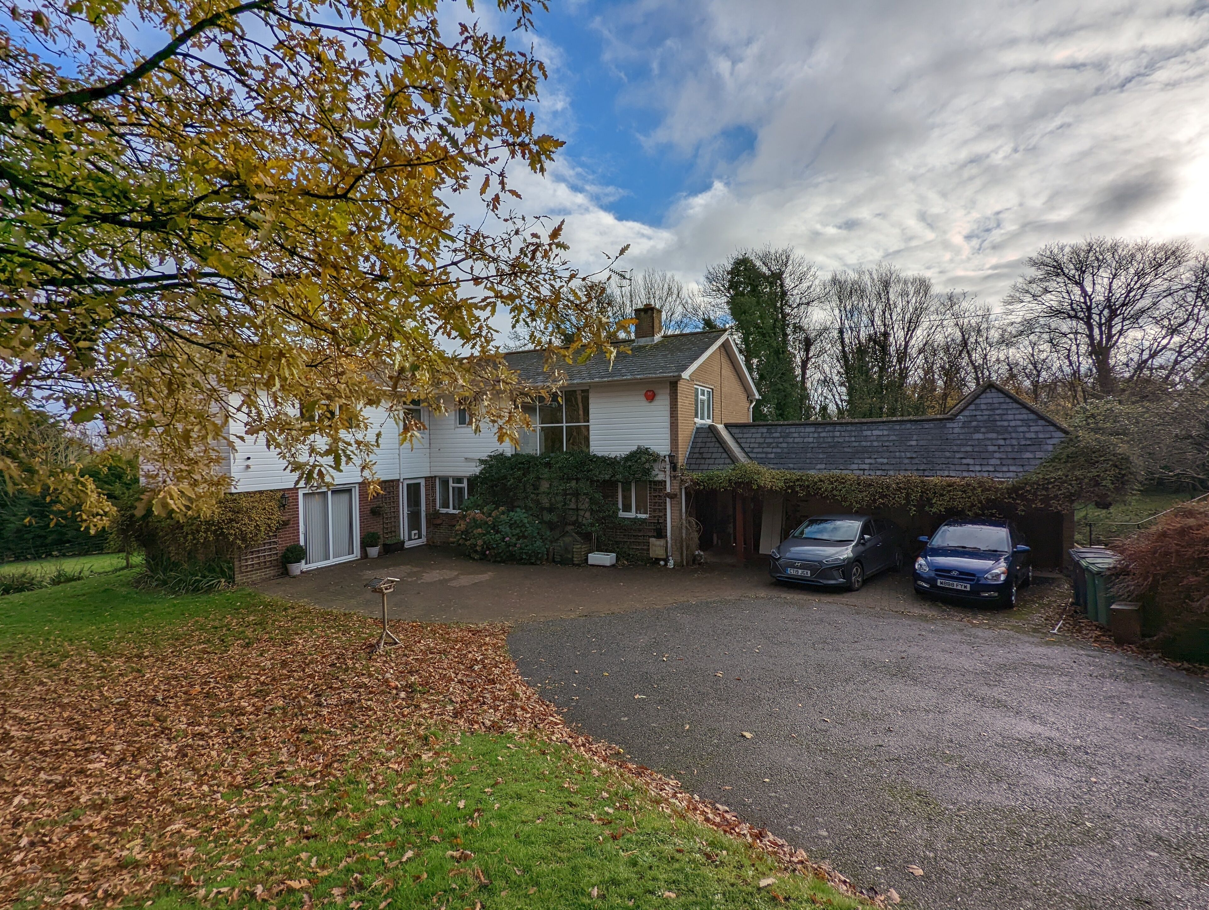 A two-story house with a garage, a driveway, and two cars parked in the garage.