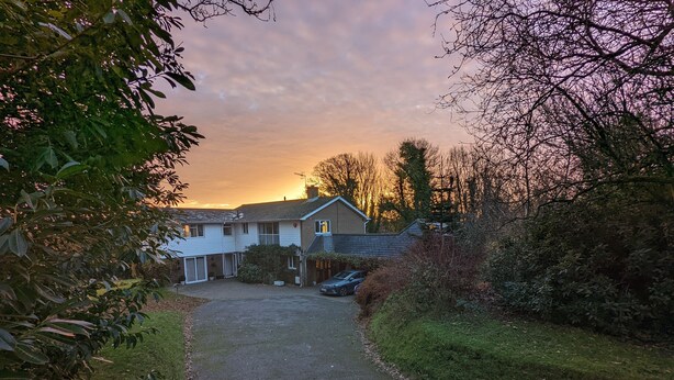 Una casa residencial amb una entrada i un camí que hi convergeix, envoltada de verdura i arbres.