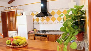 Ett kök med en bänkskiva i trä, en gasspis, ett kylskåp och en dekorativ väggbeklädnad bakom arbetsbänken.