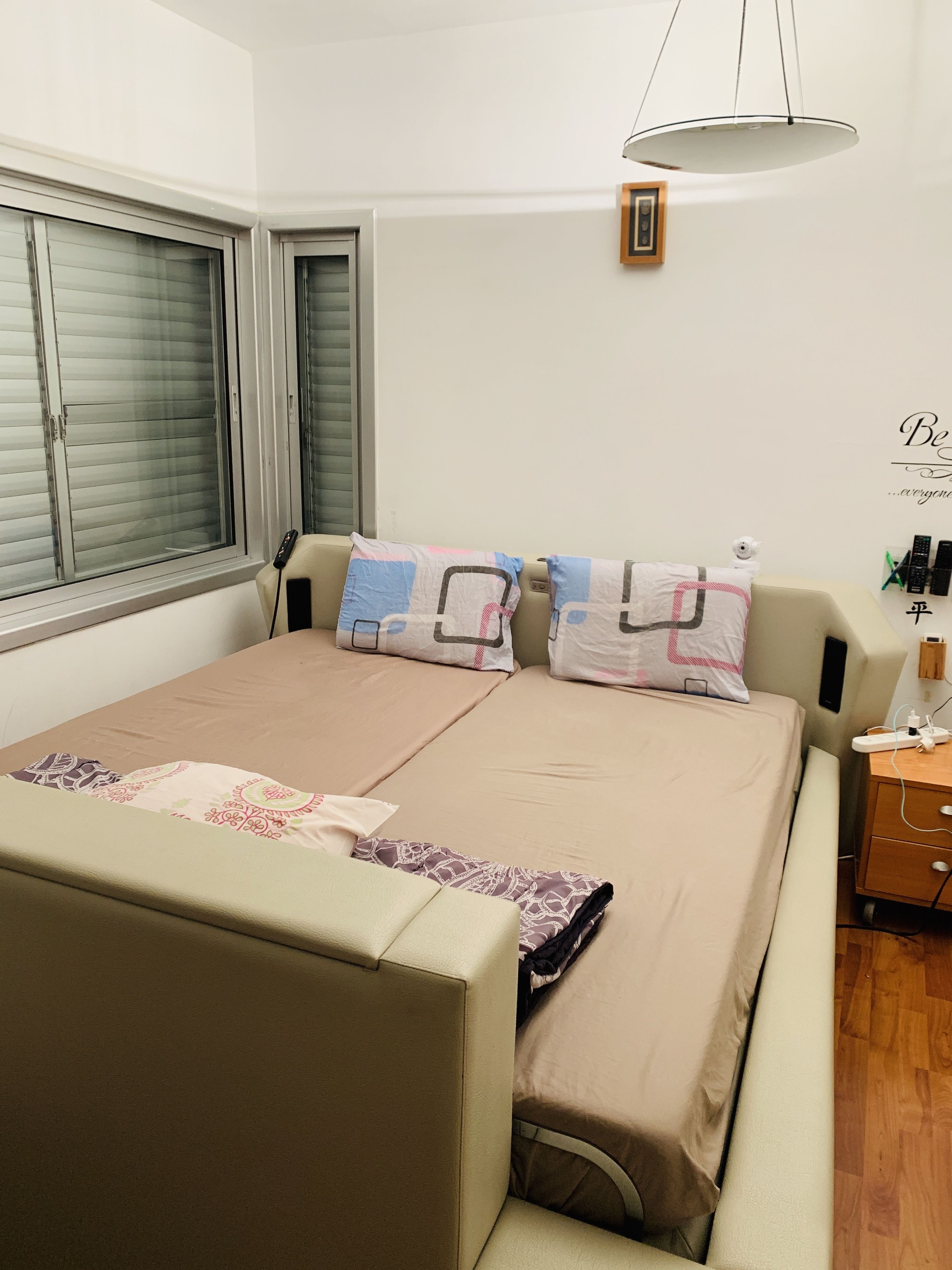 A bedroom with a bed, bedside table, and a window with blinds.