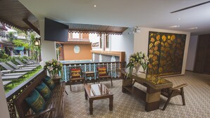 Un hall de hotel con un banco de madera, una mesa y un televisor montado en la pared.