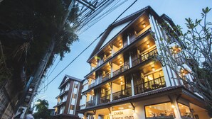 Un hotel de varios pisos con balcones, una entrada visible y señalización que indica que es un hotel Chada.