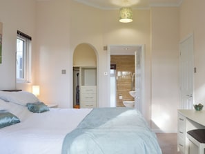 A bedroom with a bed, bedside table, and a window.