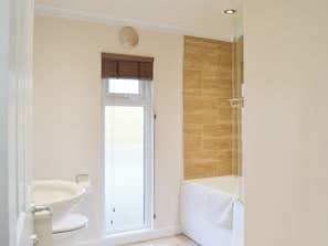A bathroom with a toilet, bidet, shower, and a towel rack.