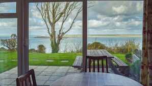 A patio with a table and chairs, overlooking a grassy area and a body of water. - 2 bedroom accommodation in Freshwater (Freshwater)