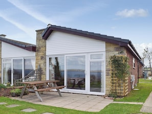 A house with a patio, a wooden table, and a stone wall.