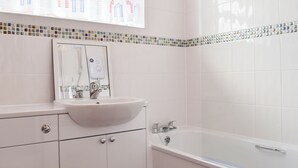 A bathroom with a white sink, mirror, and bathtub. - 2 bedroom accommodation in Freshwater (Freshwater)