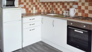 A compact kitchen with a microwave, stove, sink, and white cabinetry. - 2 bedroom accommodation in Freshwater (Freshwater)