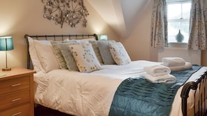 A bedroom with a bed, bedside table, lamp, decorative wall piece, window with curtains, and a radiator. - 3 bedroom accommodation in Ambleside (Ambleside)