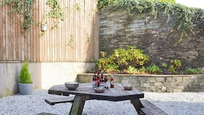 A wooden picnic table with a bowl, a metal bowl, and bottles on it. - 3 bedroom accommodation in Ambleside (Ambleside)