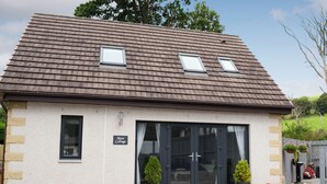 A two-story cottage with a tiled roof, a small porch with potted plants, and a sign reading "Rose Cottage." - 1 bedroom accommodation in Dingwall (Dingwall)