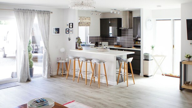 A modern kitchen with white bar stools, a dining table, and a chandelier. - 1 bedroom accommodation in Dingwall (Dingwall)