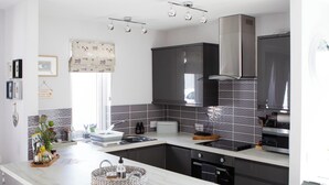 A modern kitchen with a marble countertop, dark cabinetry, and a built-in oven. - 1 bedroom accommodation in Dingwall (Dingwall)