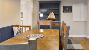 A dining area with a wooden table, chairs, pendant lights, and a sailboat model on a shelf. - 4 bedroom accommodation in Lansallos, near Looe (Lansallos, near Looe)