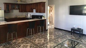 A kitchen with a central island, bar stools, a ceiling fan, and a patterned floor. - Retreat Comfortable Apartments (Falmouth)
