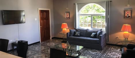 A living room with a sofa, coffee table, TV, and patterned floor.