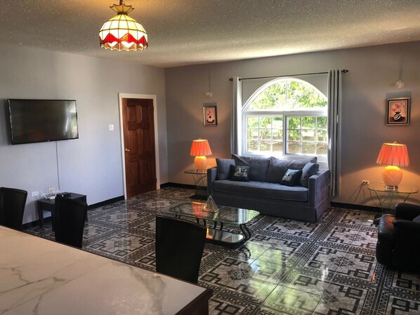 A living room with a sofa, coffee table, TV, and patterned floor.