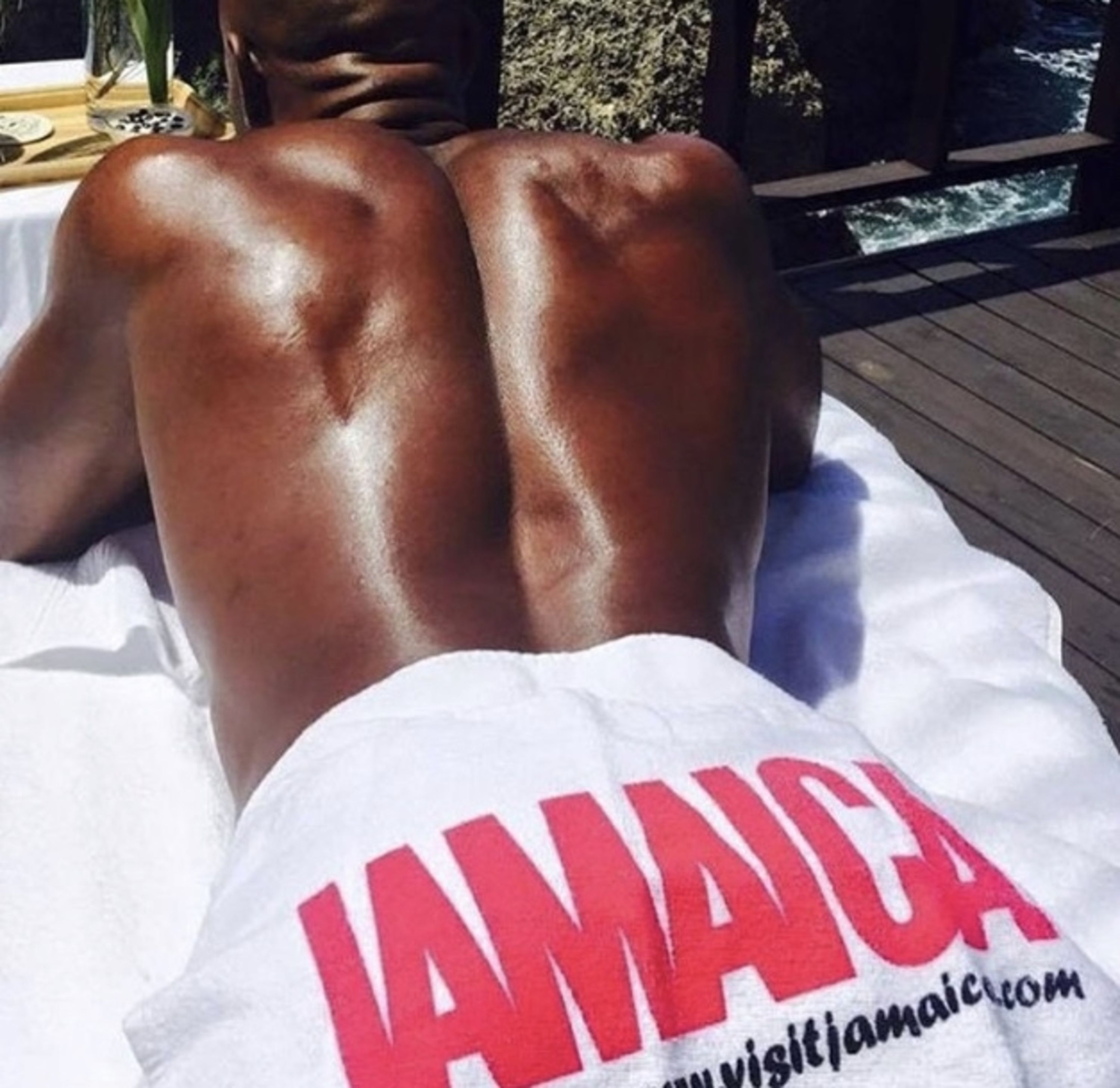 A person lying on a beach towel with the word "JAMAICA" visible on the back.