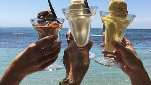 Three people holding ice cream sundaes at the beach. - Retreat Comfortable Apartments (Falmouth)