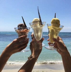 Tre personer som håller i glassbägare på stranden.