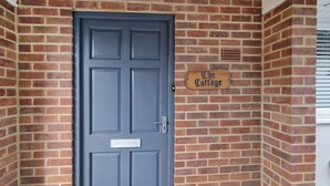 A grey door with a mailbox and a wooden sign that reads "The Cottage."