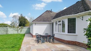 Een huis met een patio, voorzien van een stenen vloer en een tafel met stoelen.